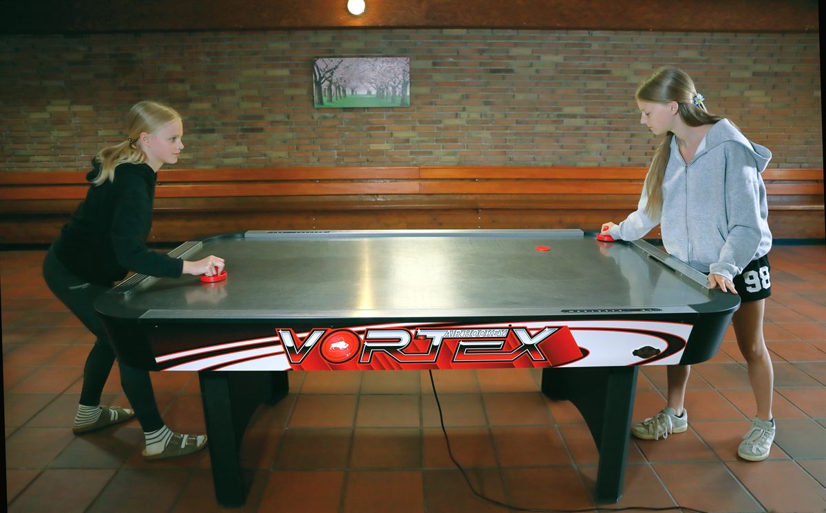 Kinder spielen Airhockey in der Tenne