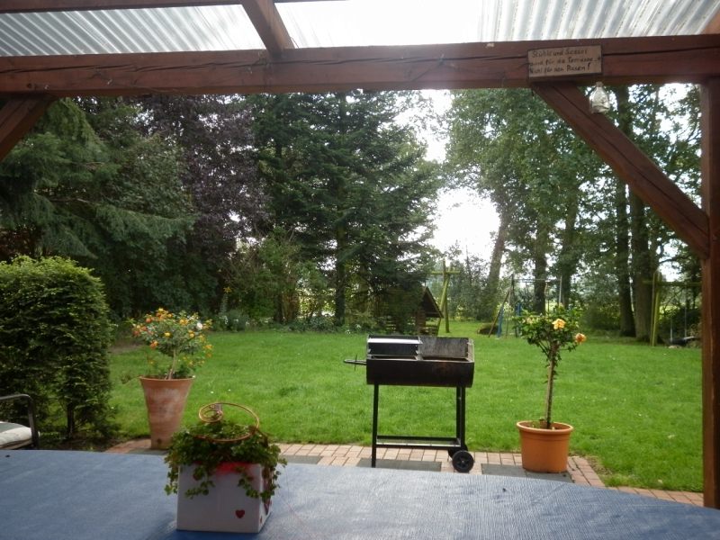 Überdachte Terrasse mit Grill und Blick in den Garten